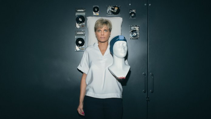 Prof. Renata Bocian trzymająca manekina z opaską Vguard w tle poduszka oraz unoszące się w przestrzeni twarde dyski komputerowe