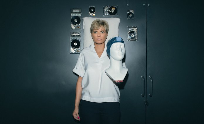 Prof. Renata Bocian trzymająca manekina z opaską Vguard w tle poduszka oraz unoszące się w przestrzeni twarde dyski komputerowe