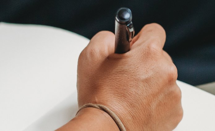 Zdjęcie dłoni trzymającej długopis, gotowej do robienia notatek