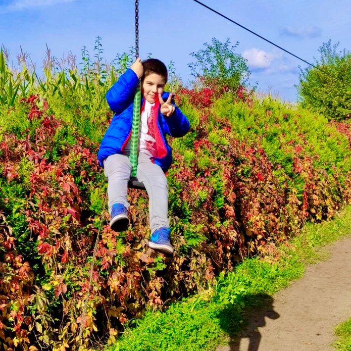 [Translate to English:] Chłopiec w niebieskiej kurtce huśtawce