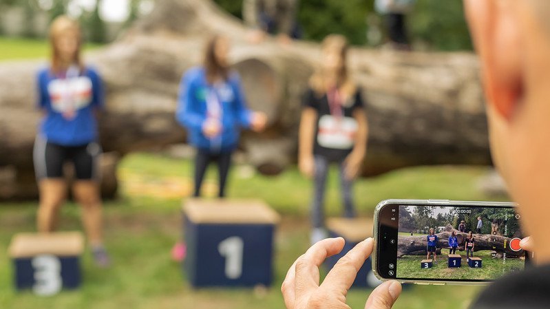 A person taking a photo of the athletes standing on the podium