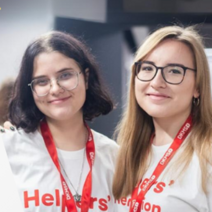 2 młode kobiety w białych koszulkach z napisem Helpers' Generation