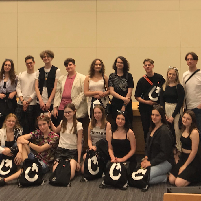 Grupa młodych ludzi stojących w sali wykładowej