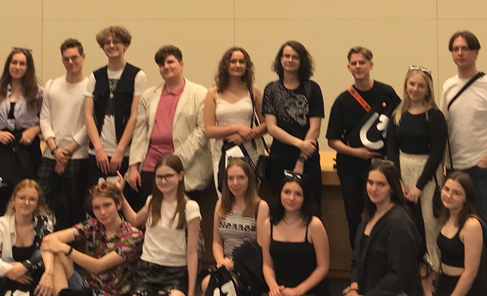 Grupa młodych ludzi stojących w sali wykładowej