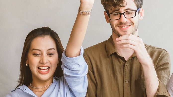 a young woman with her arms raised and a young smiling man