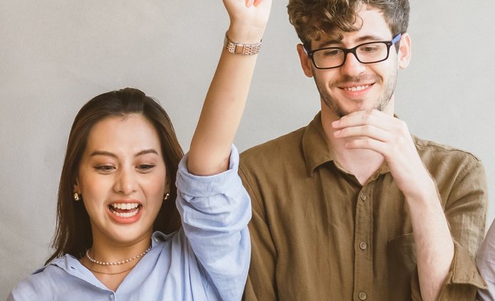 a young woman with her arms raised and a young smiling man