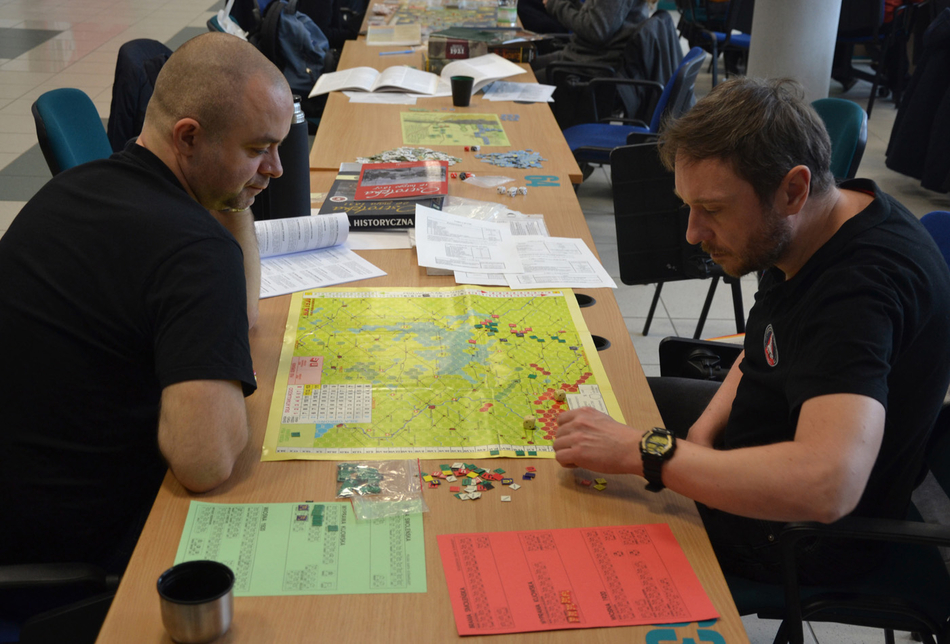 osoby uczestniczące w grze siedzące wokół stołu z grą osoby uczestniczące w grze siedzące wokół stołu z grą