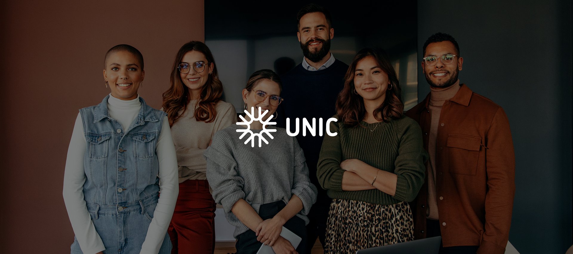 stojąca grupa ludzi z logo unic