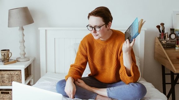 Osoba ucząca się na łóżku przed komputerem
