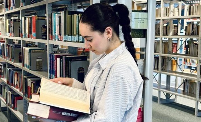 kobieta trzymająca książkę w budynku biblioteki