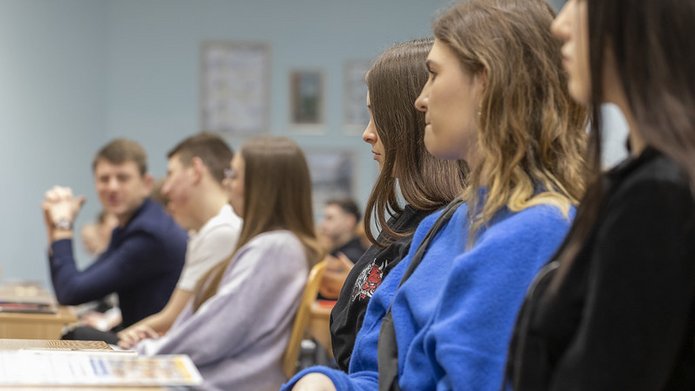 kolorowe zdjęcie przedstawiające z profilu grupę studentów siedzących w ławkach