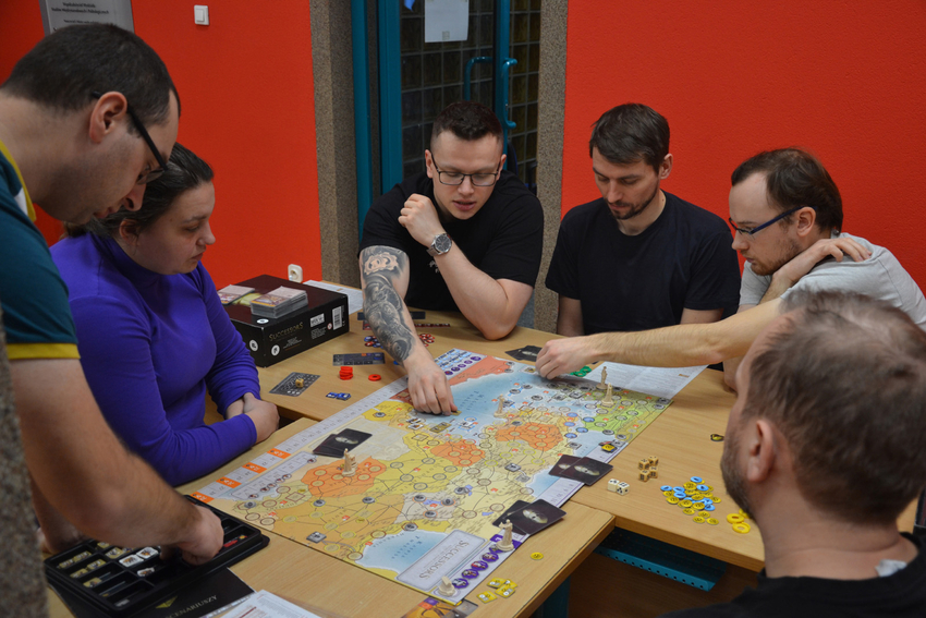 osoby uczestniczące w grze siedzące wokół stołu z grą osoby uczestniczące w grze siedzące wokół stołu z grą