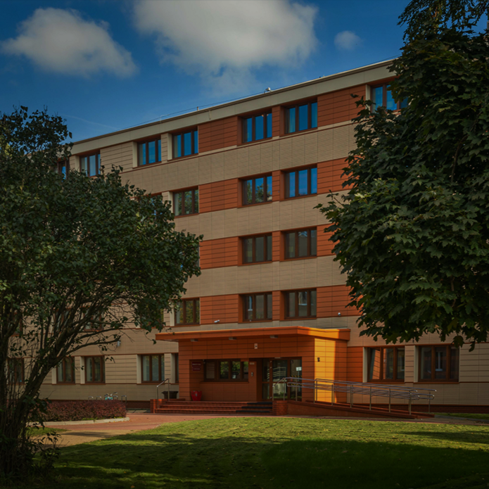 The photo shows a University of Lodz dormitory building surrounded by greenery. A large tree is in the foreground, with the dormitory entrance behind it. On the left side of the graphic is a white inscription: "Find your place. Recruitment for the University of Lodz dormitories." In the upper right corner, a red arrow points up and to the right.