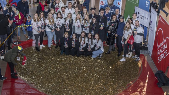 The University of Lodz students standing next to a huge heart made of gold coins 