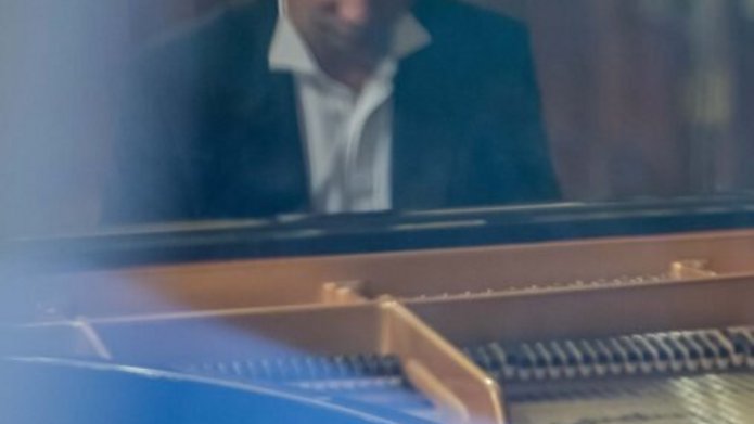 A man wearing a suit at the grand piano