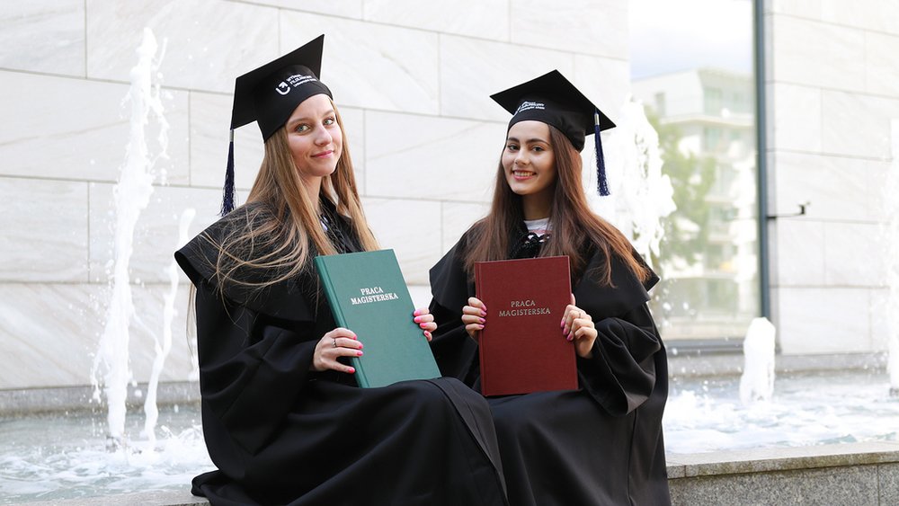 Absolwentki trzymające prace magisterskie