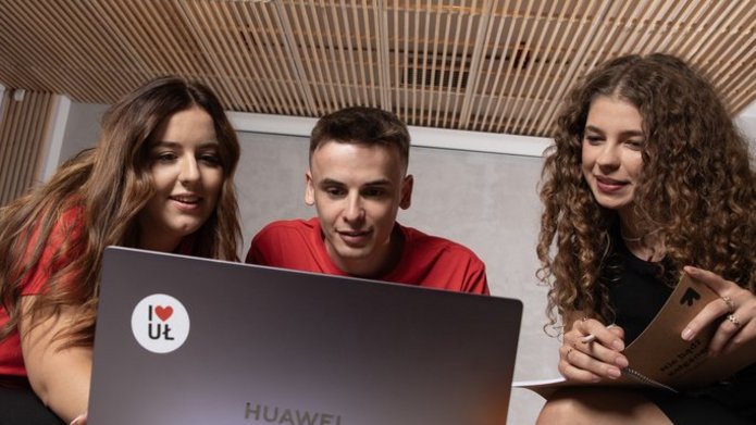 Dwie studentki i student pracują wspólnie przed otwartym laptopem.