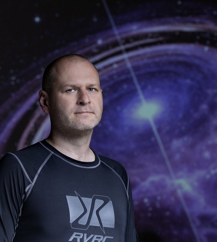 dr Michał Szanecki against the background of a photo with a neutron star