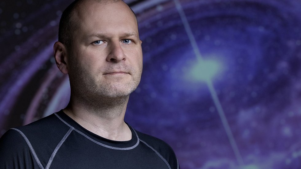 dr Michał Szanecki against the background of a photo with a neutron star