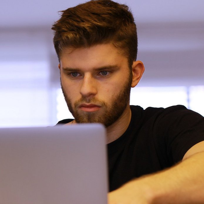 Młody człowiek patrzy w ekran komputera.