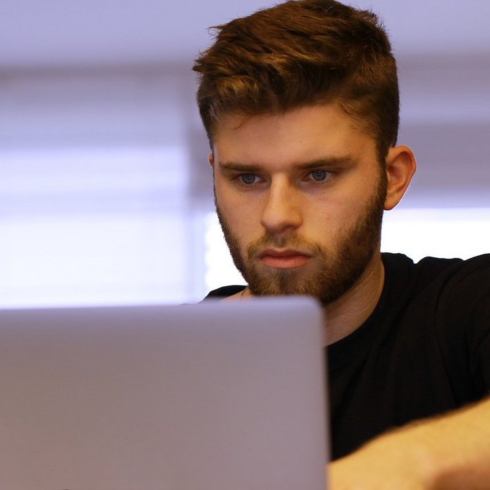 Zdjęcie poglądowe. Chłopak z zainteresowaniem patrzy w ekran komputera.