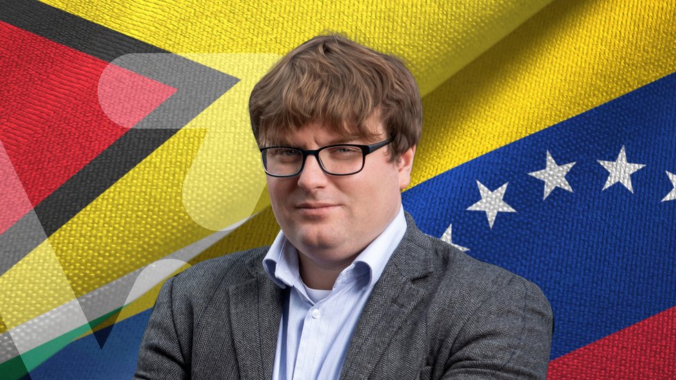 A portrait photo of Dr Mateusz Piątkowski on the background of the flags of Venezuela and Guyana