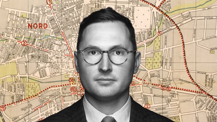 Dr Adam Sitarek on the background of a fragment of the map of the Lodz ghetto