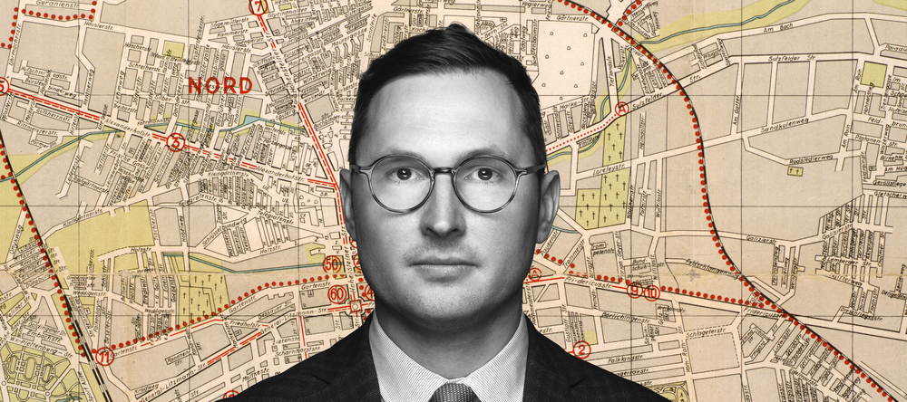 Dr Adam Sitarek on the background of a fragment of the map of the Lodz ghetto