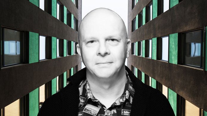 A portrait photo of Dr Tomasz Napierała between two soaring office buildings