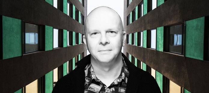 Portret dra Tomasza Napierały pomiędzy dwoma strzelistymi budynkami biurowymi