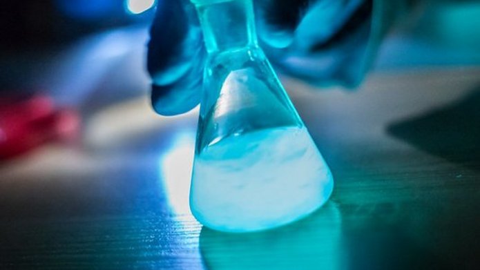Zlewka z fluorescencyjną, świecącą na niebiesko cieczą