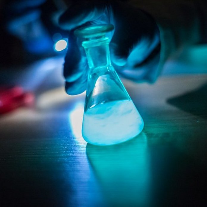 Zlewka z fluorescencyjną, świecącą na niebiesko cieczą