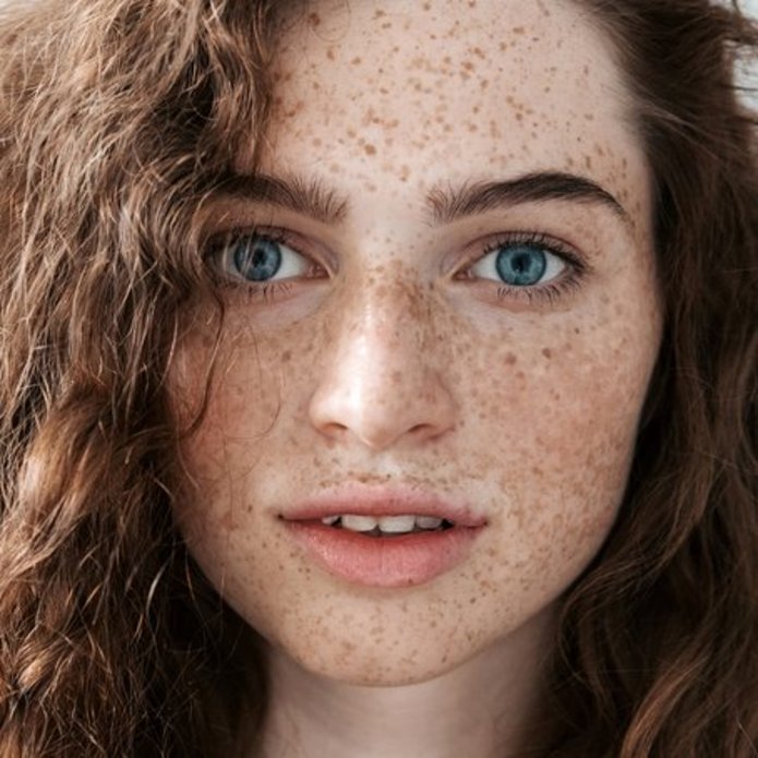 Twarz młodej kobiety o niebieskich oczach z kręconymi włosami