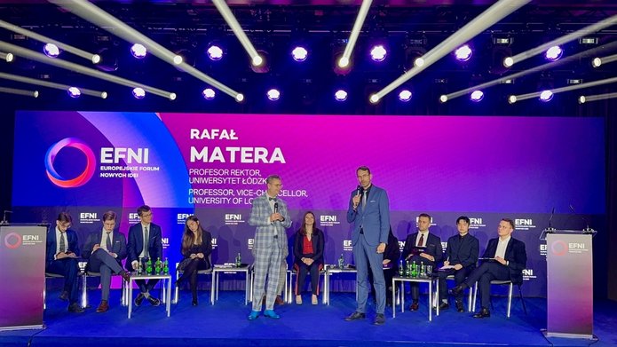 Rektorzy SGH i UŁ na scenie podczas EFNI, stojący obok siebie, z mikrofonami, w tle widać uczestników wydarzenia.