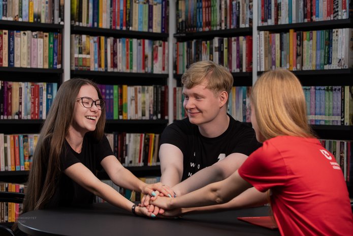 trójka studentów siedzi przy stole