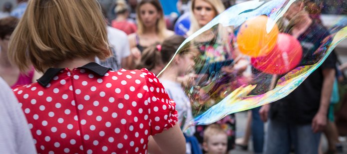 A woman in a red dress with white polka dots and a large soap bubble