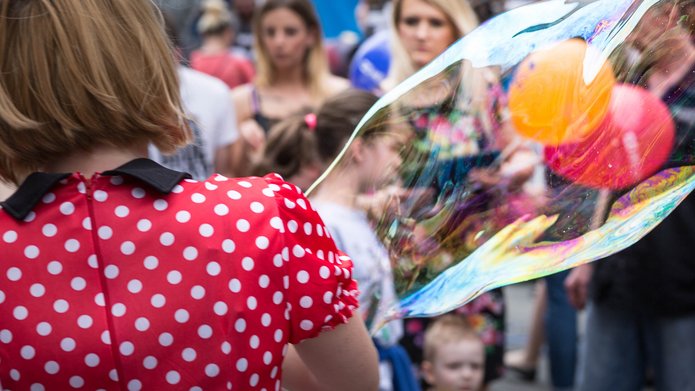 Kobieta w czerwonej sukience w białe grochy i duża bańka mydlana