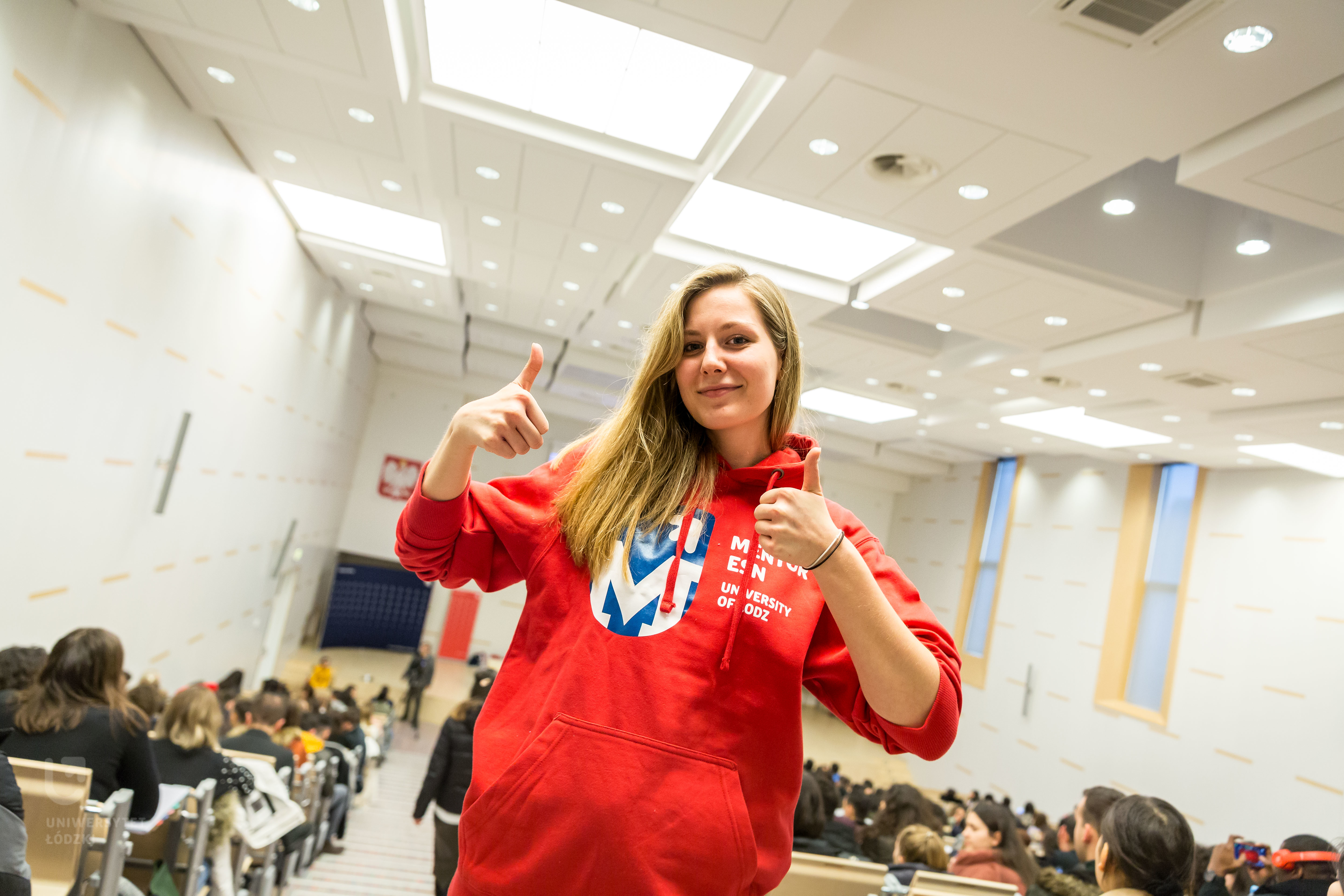 Dziewczyna unosząca kciuki w górę w bluzie Uniwersytetu Łódzkiego
