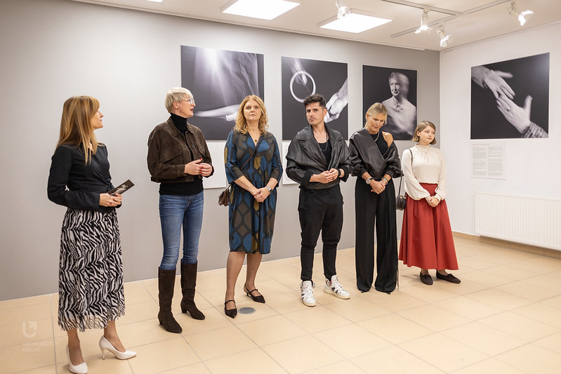 Grupa osób stoi na środku galerii podczas wernisażu