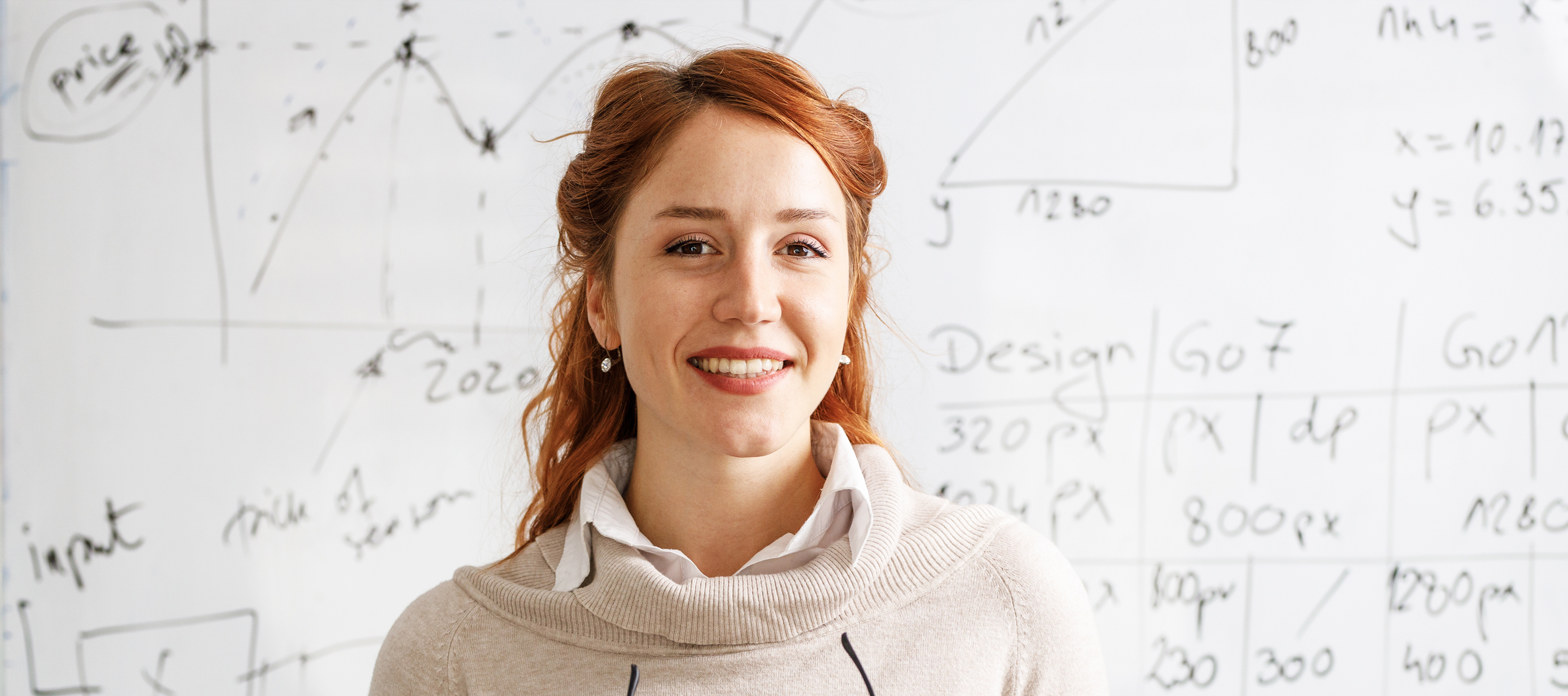 a portrait of a smiling woman against a white board with black lettering 