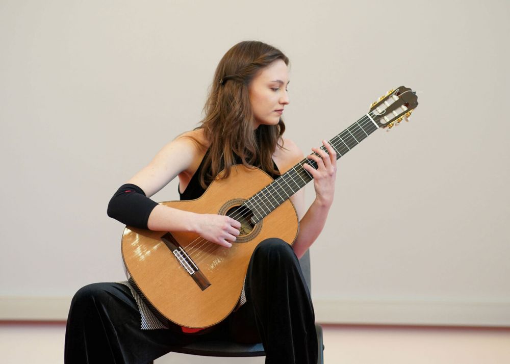 Kalina Polańska who is sitting and playing the guitar
