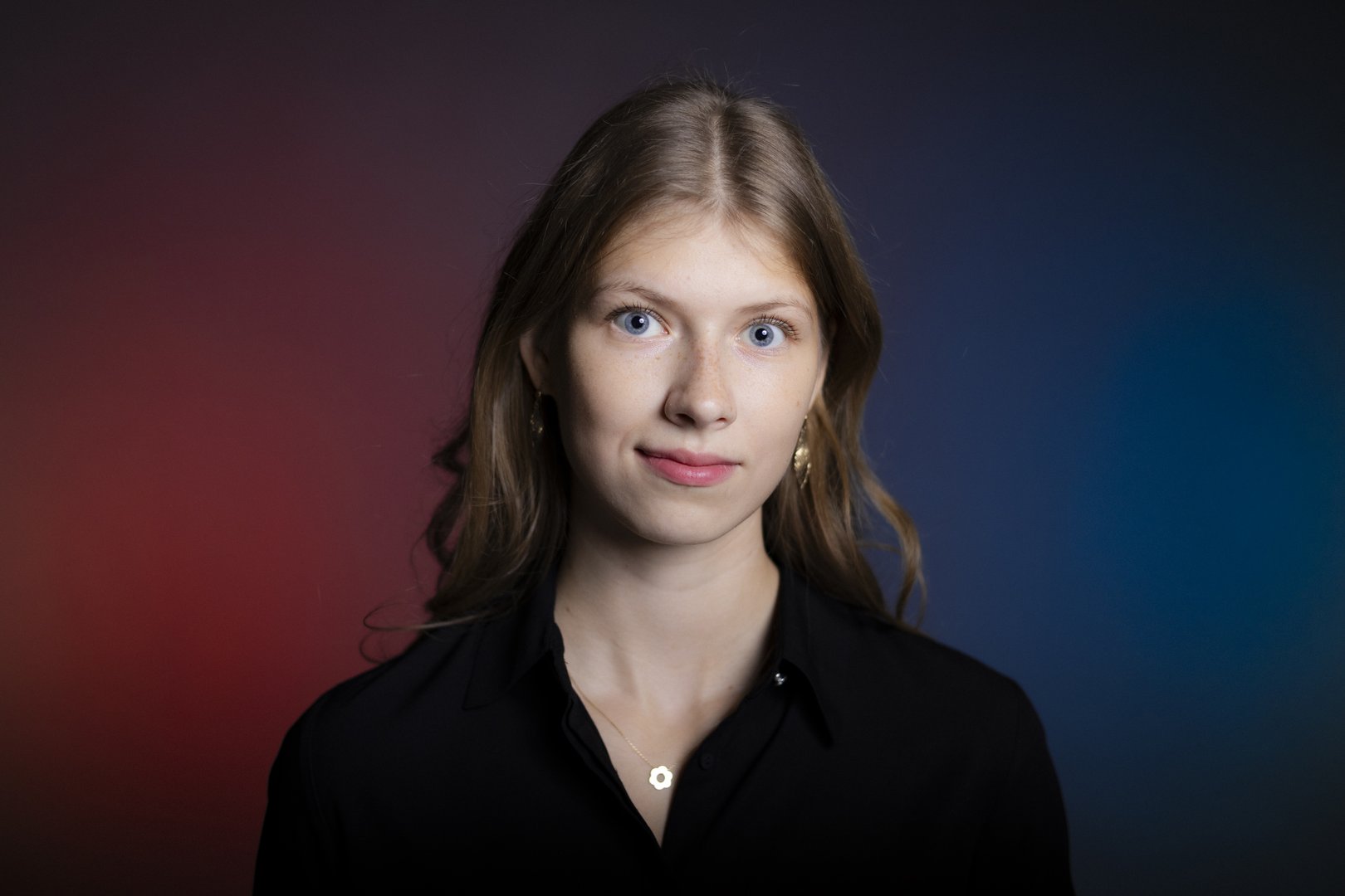 Blond dziewczyna z długimi włosami na tle fioletowo granatowej ściany