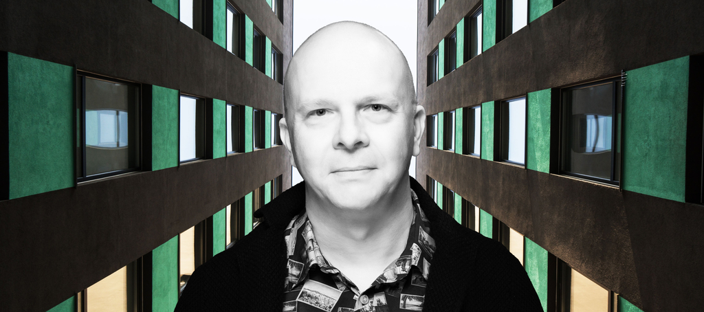 Portret dra Tomasza Napierały pomiędzy dwoma strzelistymi budynkami biurowymi