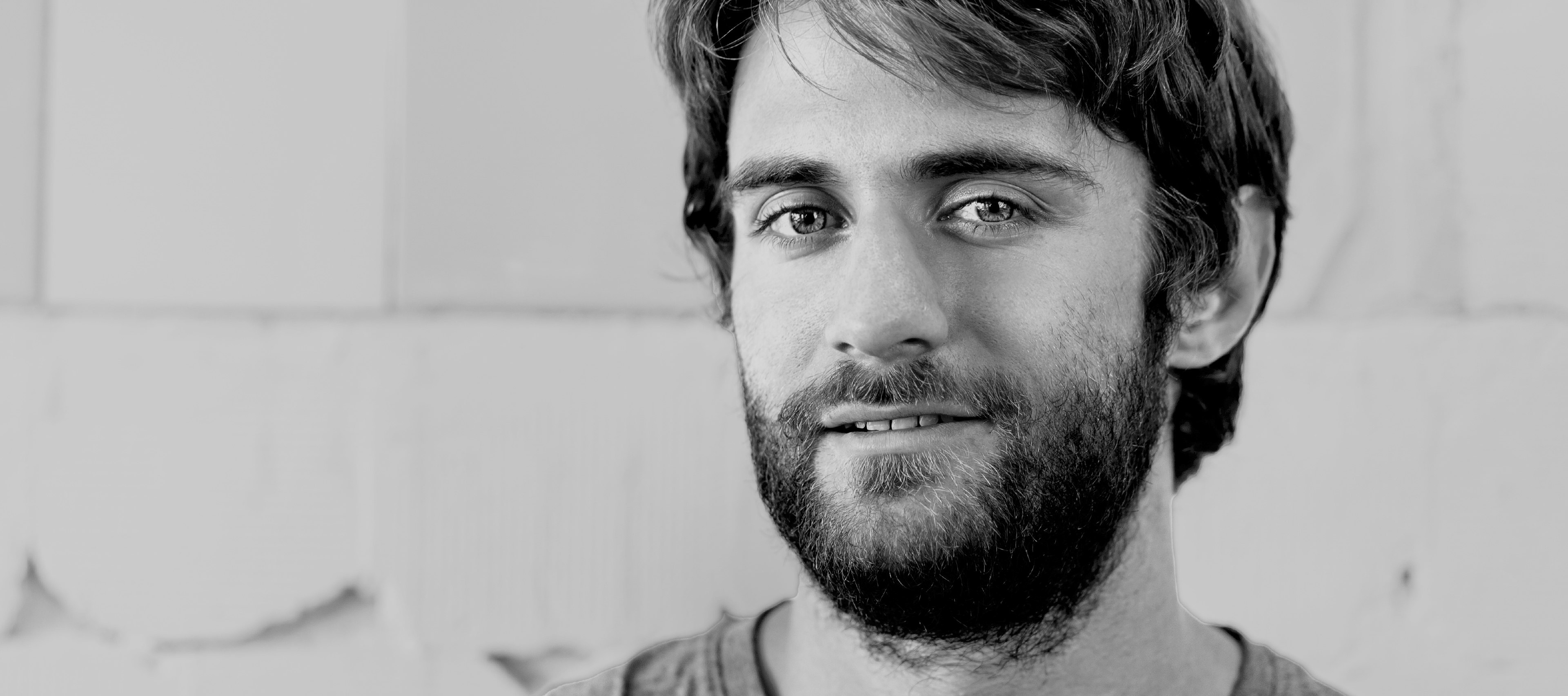 czarno-białe zdjęcie przedstawiające młodego mężczyznę z zarostem; zdjęcie ilustruje artykuł poświęcony drzwiom otwartym szkół doktorskich UŁ