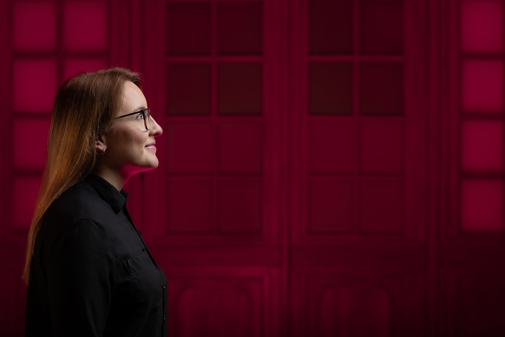 Zdjęcie przedstawia profil studentki na czerwonym tle.