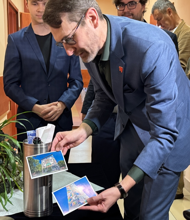 rektor UŁ pokazuje zdjęcia obiektów UŁ, które trafią do kapsuły