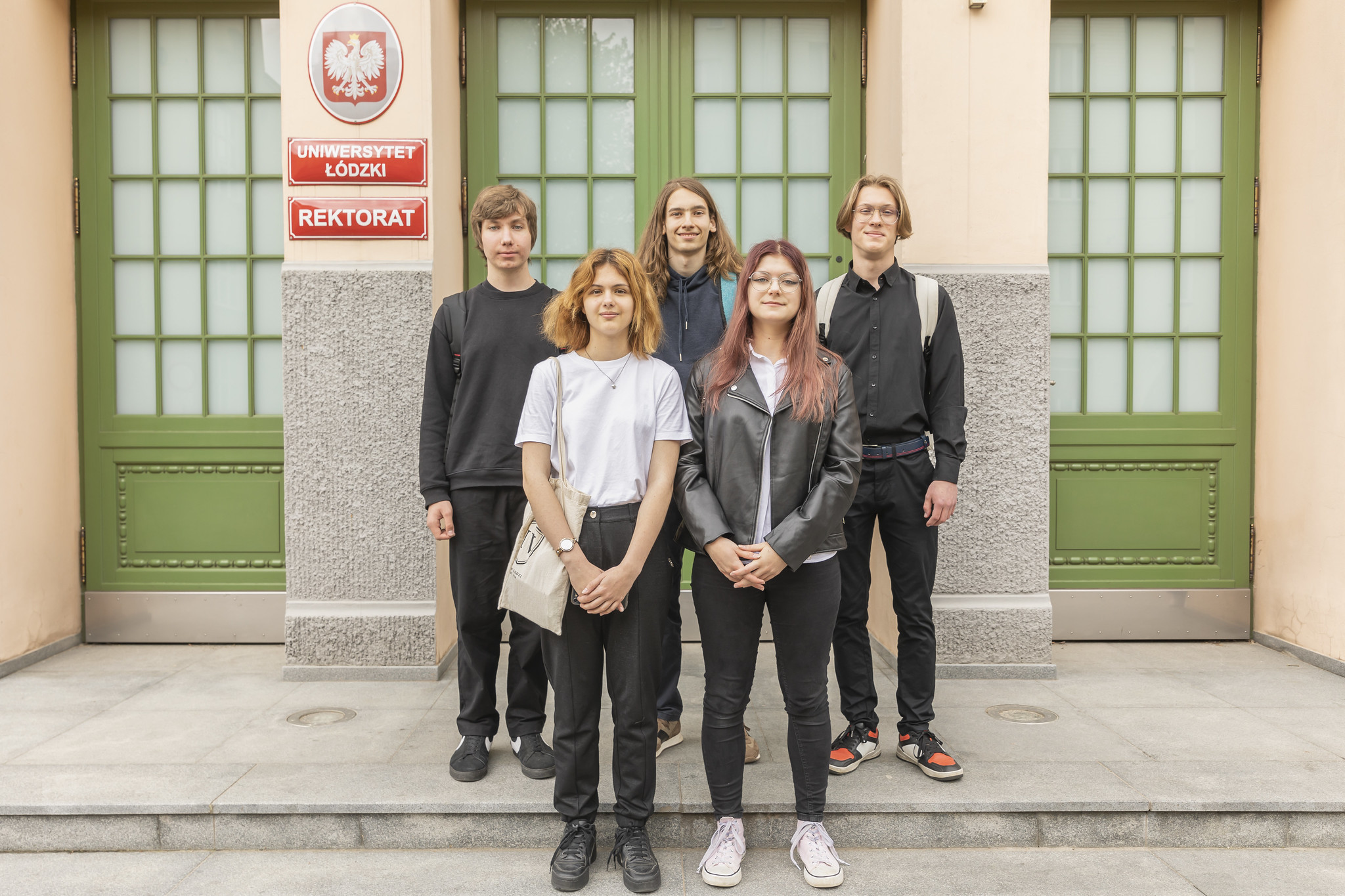 5 uczniów stojących przed budynkiem Rektoratu UŁ