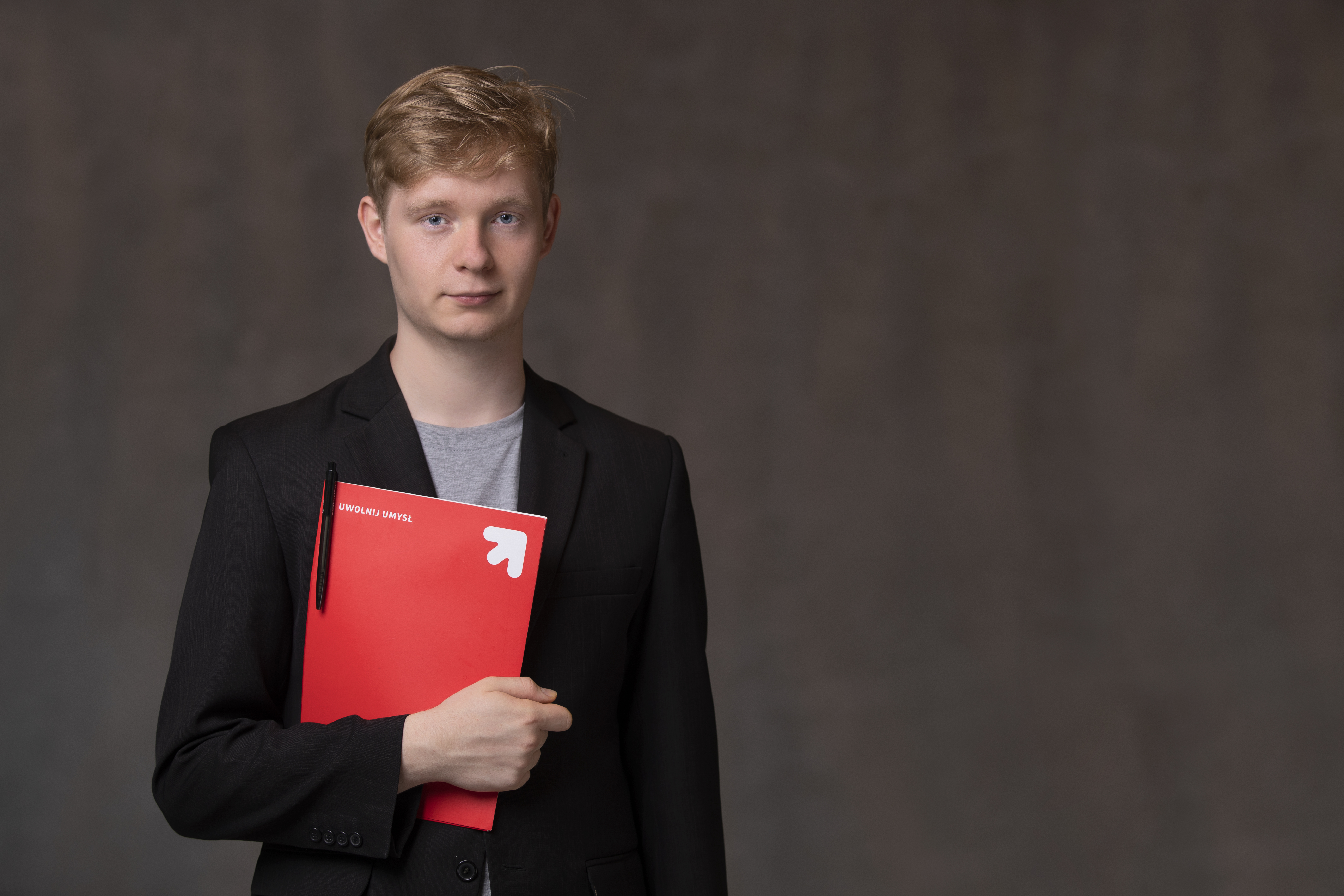 Młody mężcyzna trzymający teczkę papierową z napisem Uwolnij umysł