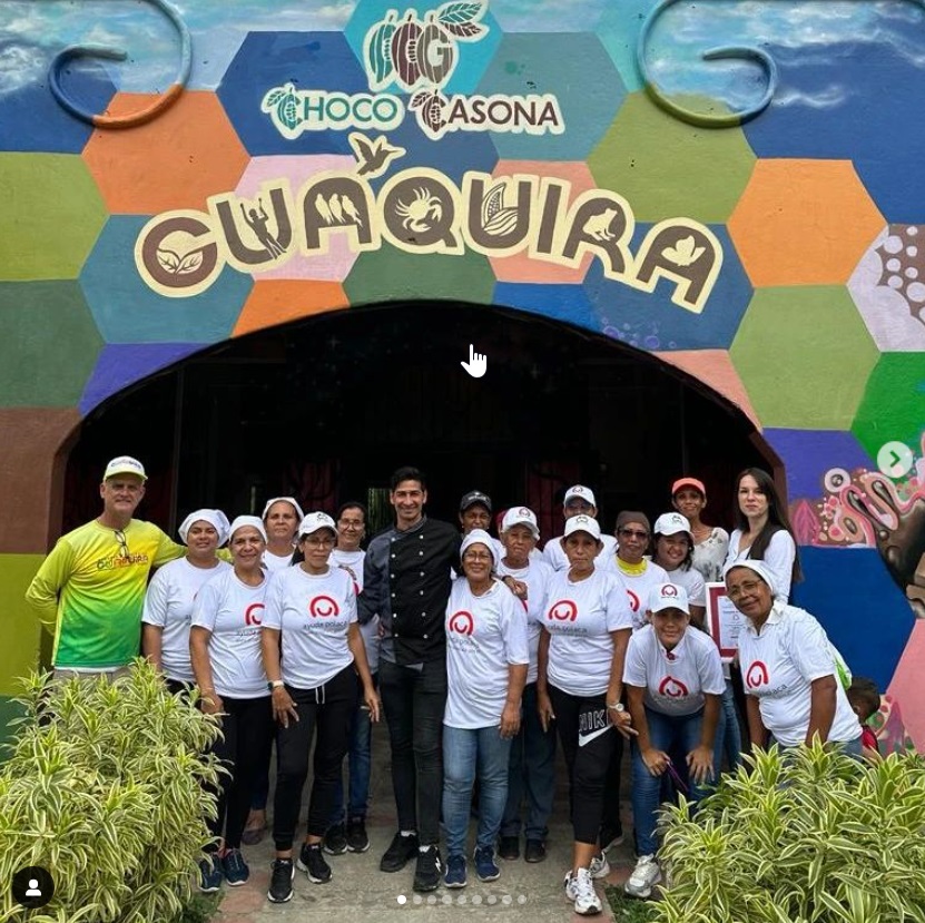 Grupa ludzi przed kolorowym wejściem do warsztatu czekolady