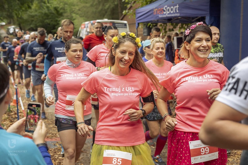 Grupa ludzi biegnie przez las w zawodach sportowych